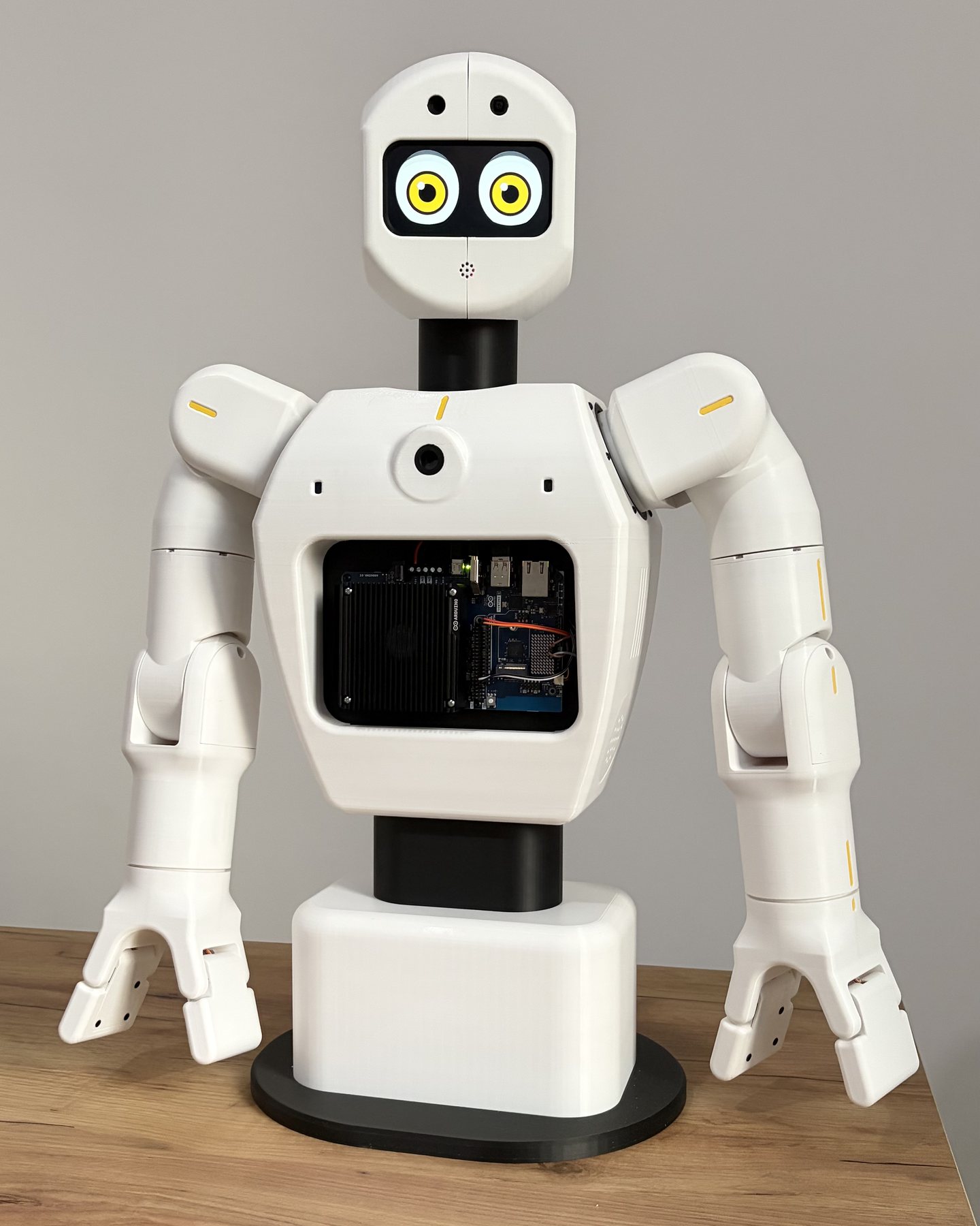 Il robot su un tavolo di legno, visto di fronte: gli occhi sullo schermo del viso, la scheda visibile dalla finestra del petto
