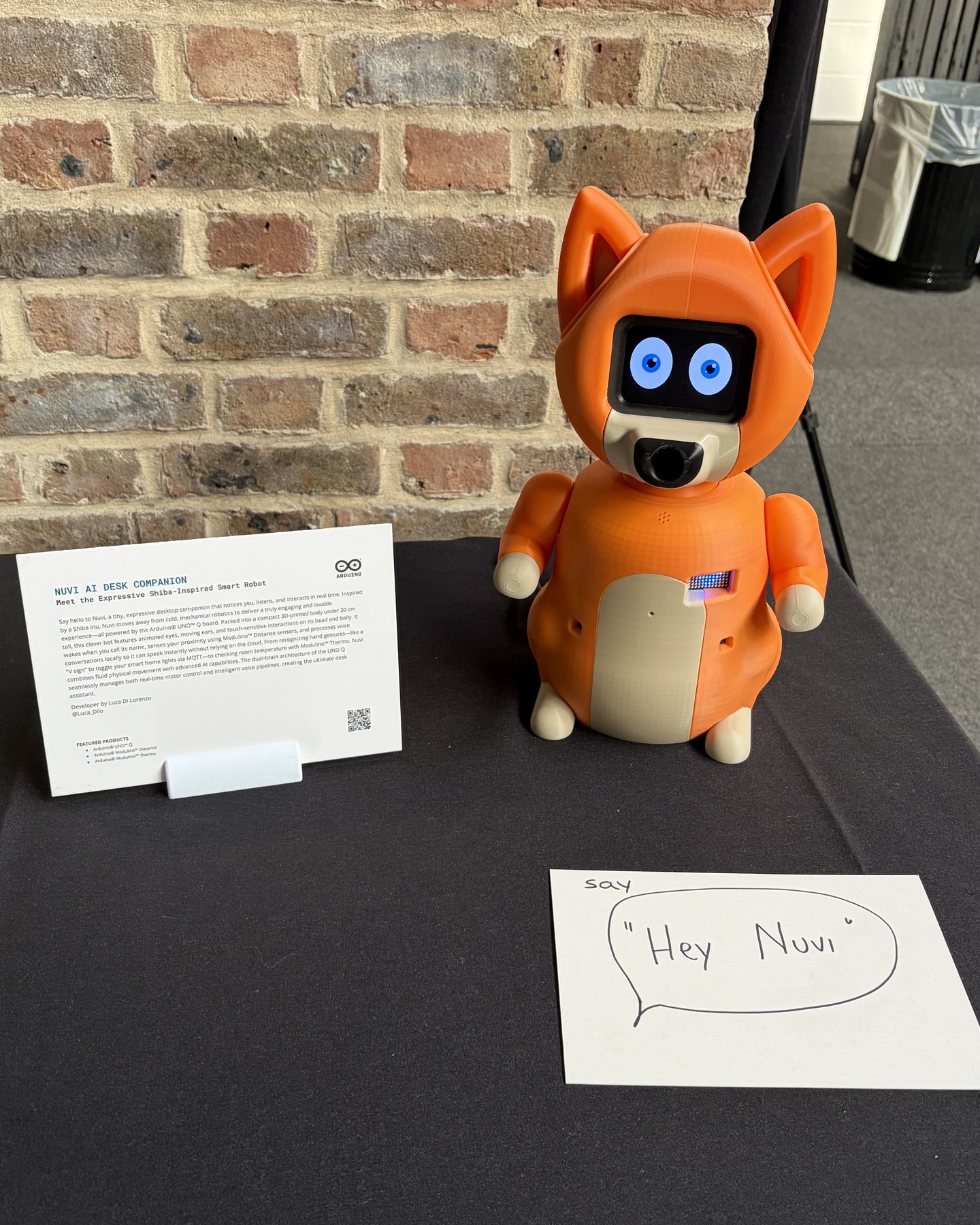 Nuvi esposto a un evento Arduino, accanto alla sua targa e a un cartello con scritto «Hey Nuvi»