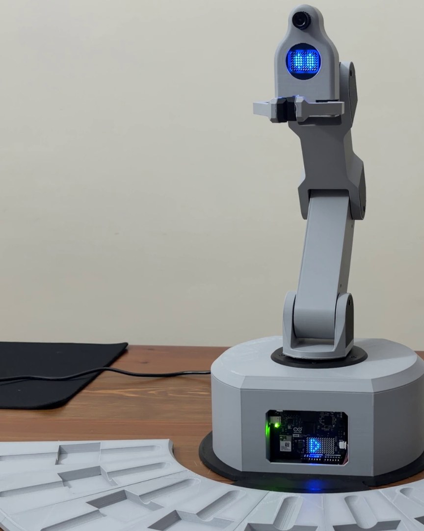 Il braccio sulla sua base, la faccia LED accesa, i vassoi davanti